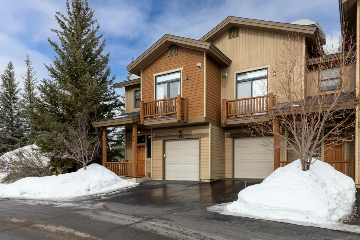 Another exterior shot featuring wooden balconies and a snow-covered outdoor area with pine trees, highlighting the inviting transition between indoor comfort and natural surroundings. The soft dusk light suggests the perfect setting for enjoying evening sunsets together as a family.